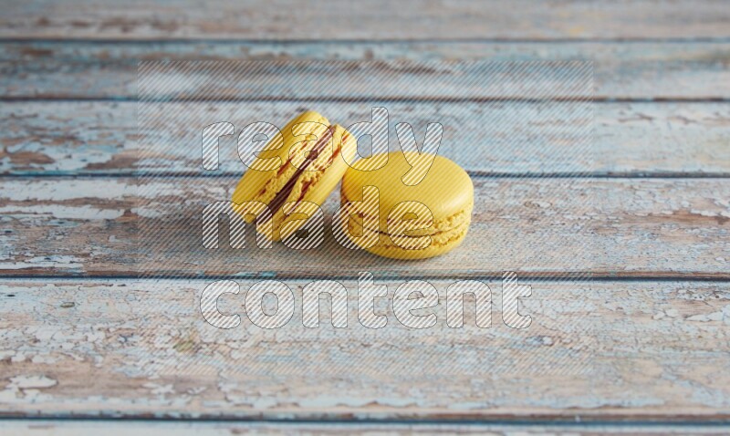 45º Shot of two Yellow Lemon macarons on light blue wooden background