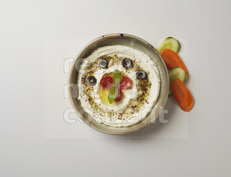 Lebnah garnished with cherry tomato, mint, olives & pine nuts in a grey pottery plate on a white background