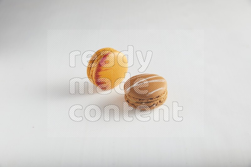 45º Shot of of two assorted Brown Irish Cream, and Orange Exotic macarons on white background