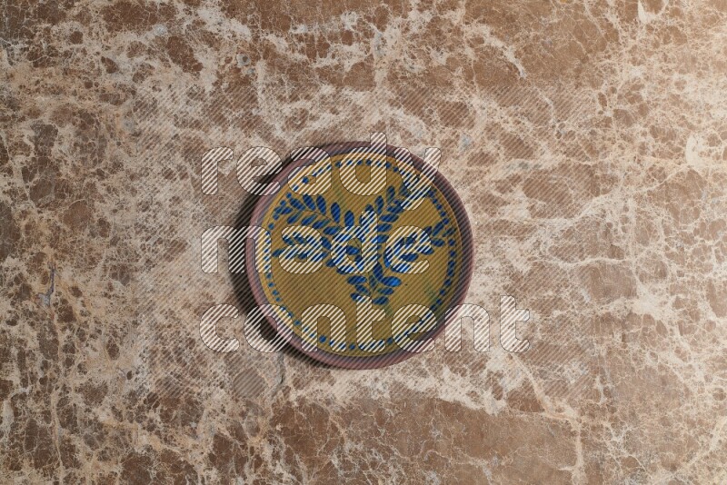 A decorative pottery plate on beige marble background