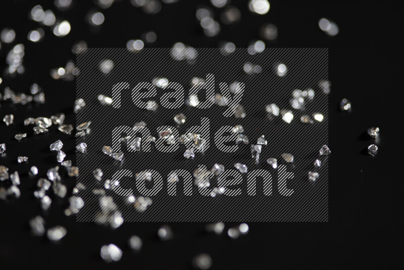 قطع زجاجية فضية لامعة متناثرة على خلفية سوداء