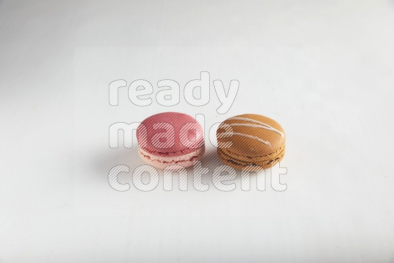 45º Shot of of two assorted Brown Irish Cream, and Pink Litchi Raspberry macarons on white background