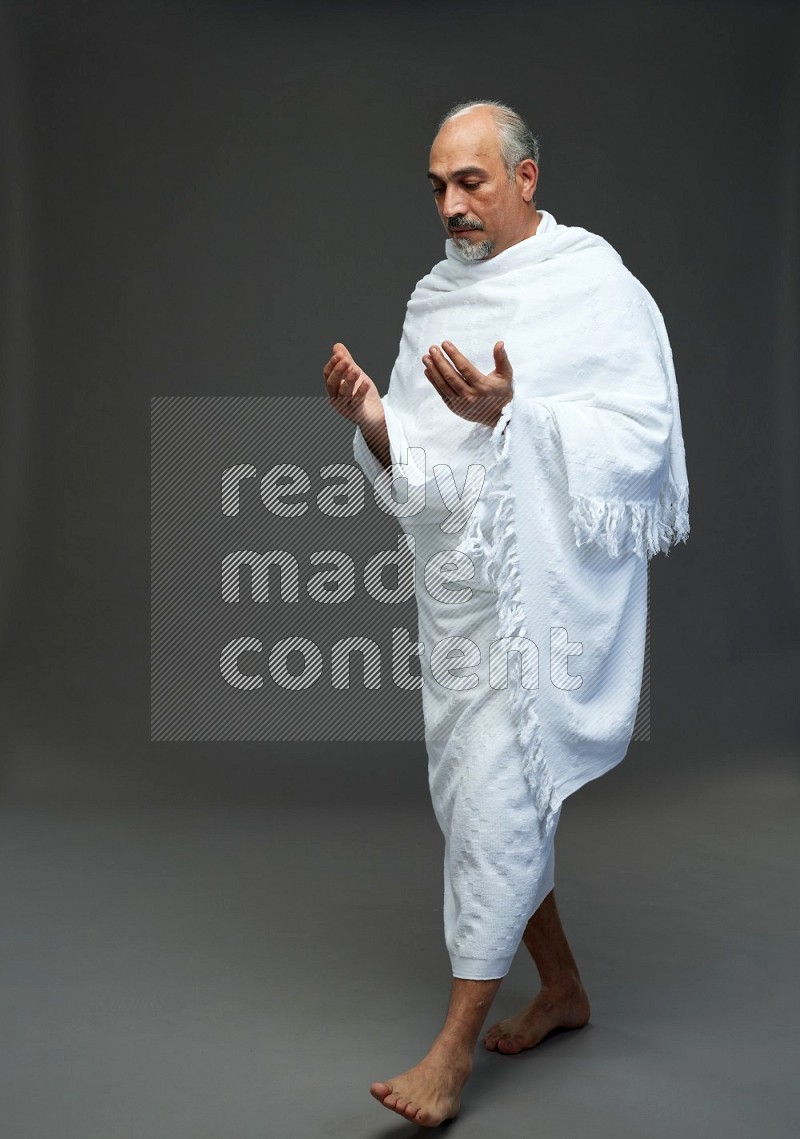 A man wearing Ehram Standing dua'a on gray background