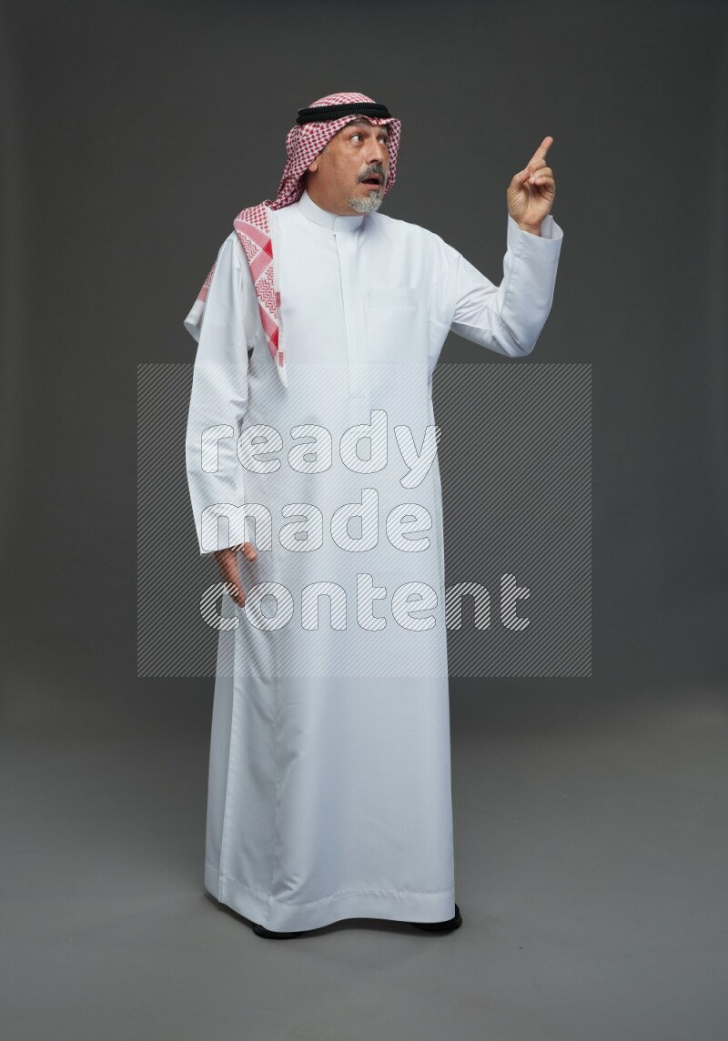 Saudi man with shomag Standing Interacting with the camera on gray background