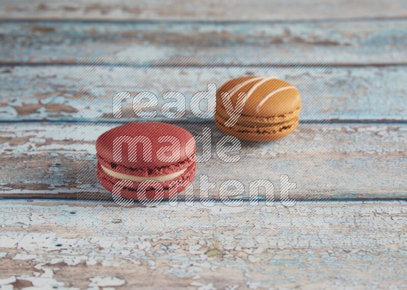 45º Shot of of two assorted Brown Irish Cream, and Red Velvet macarons on light blue background