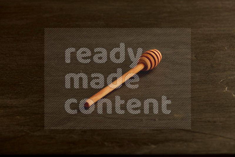 Wooden honey dipper on black slate background