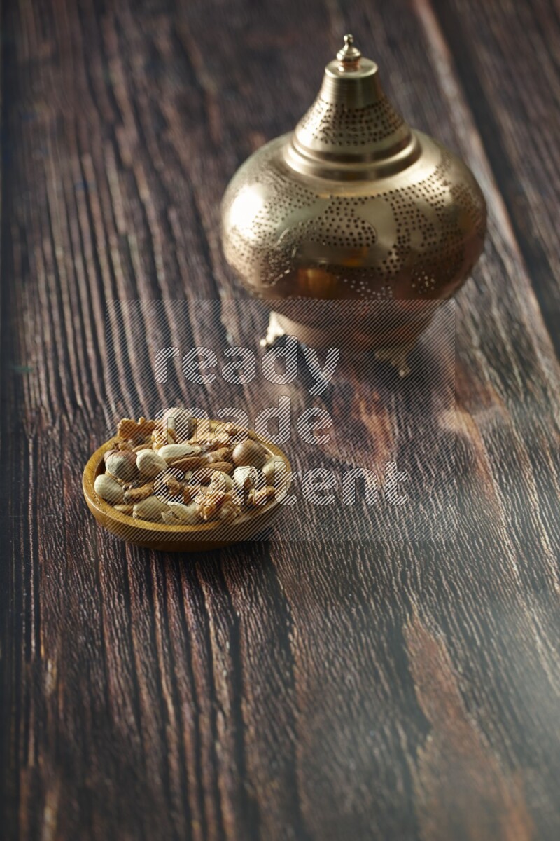 A golden lantern with different drinks, dates, nuts, prayer beads and quran on brown wooden background