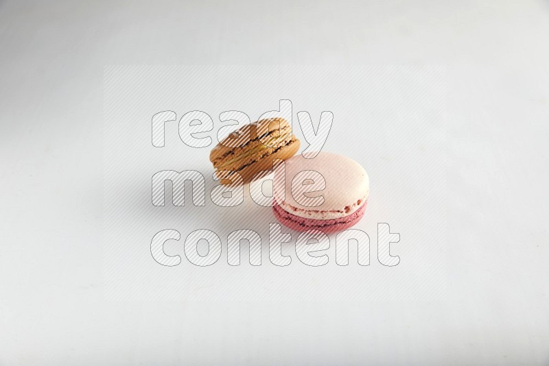 45º Shot of of two assorted Brown Irish Cream, and Pink Litchi Raspberry macarons on white background