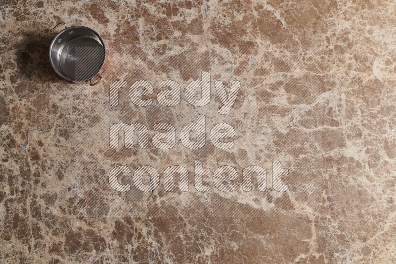 A small copper pot on beige marble background