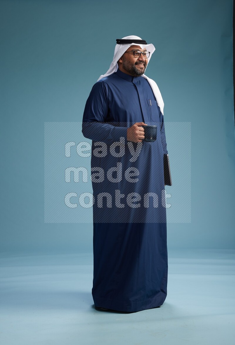 Saudi Man with shimag Standing drinking coffee on blue background