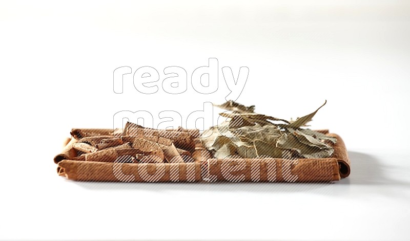 2 squares of cinnamon sticks full of cinnamon and bay laurel leaves on white flooring