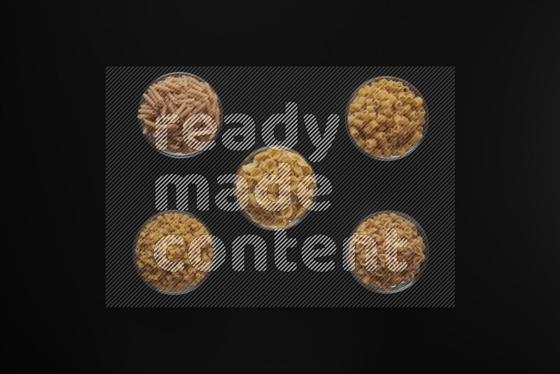 أنواع مختلفة من المعكرونة في أوعية زجاجية علي خلفية سوداء