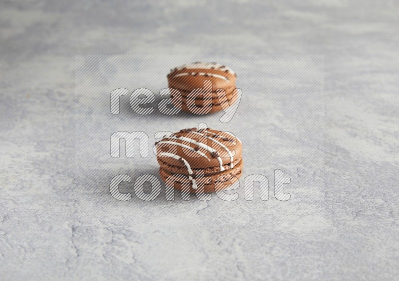 45º Shot of two Brown white marbleChocolate Caramel macarons  on white  marble background