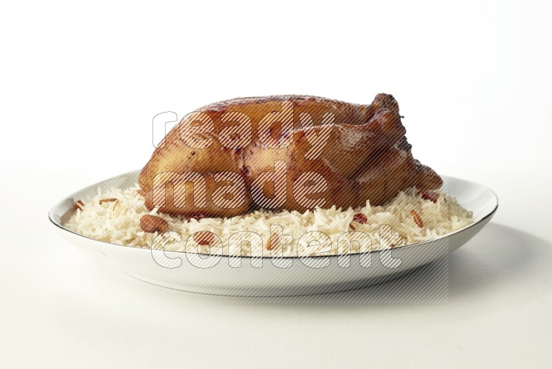 white  basmati Rice with  whole roasted chicken  on a white plate with a silver rim direct  on white background