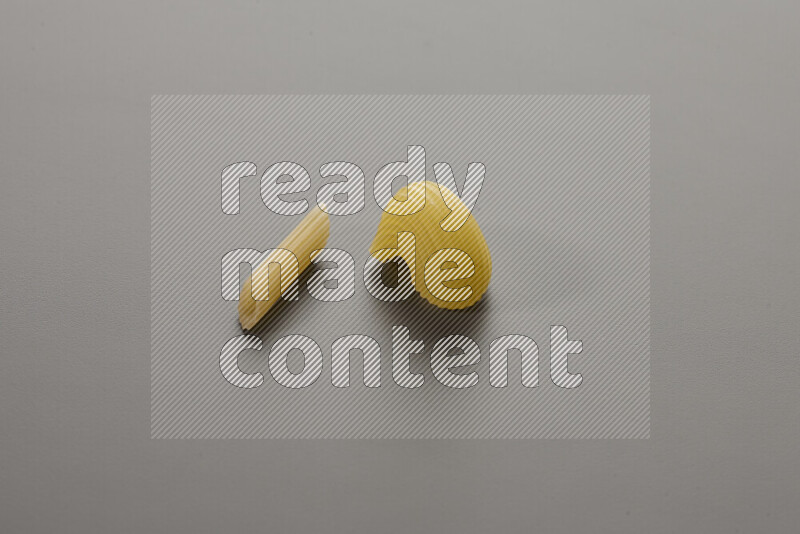 Mini penne pasta with other types of pasta on grey background