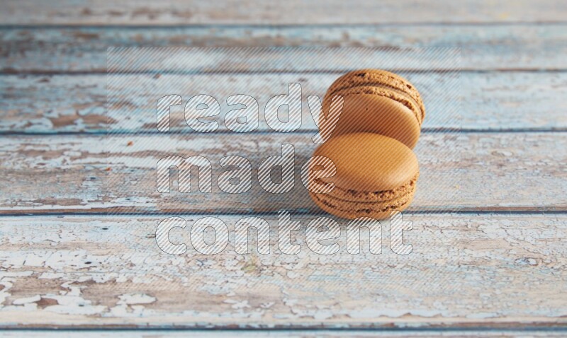 45º Shot of two Brown Maple Taffy macarons on light blue wooden background