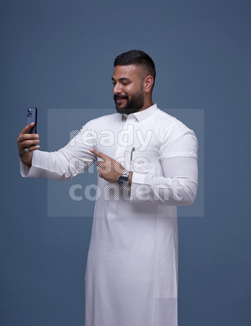 A Saudi man Taking A Selfie on Blue Background wearing Saudi Thob
