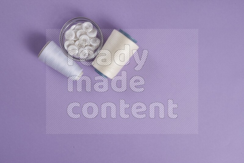 مجموعة من أدوات الخياطة والتفصيل بيضاء وأرجوانية اللون على خلفية أرجوانية