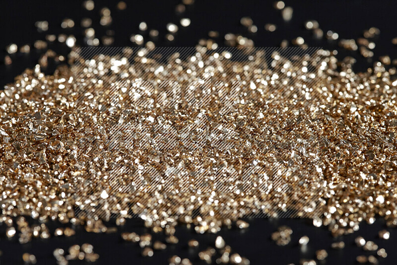 Gold shimmering fragments of glass scattered on a black background