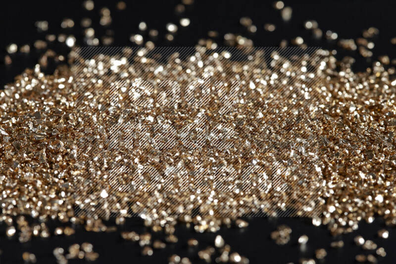 Gold shimmering fragments of glass scattered on a black background