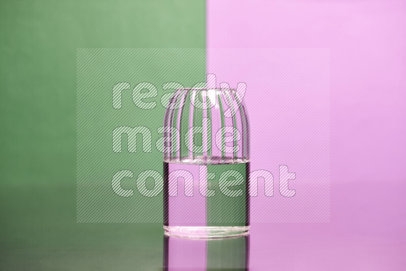 The image features a clear glassware filled with water, set against green and light purple background