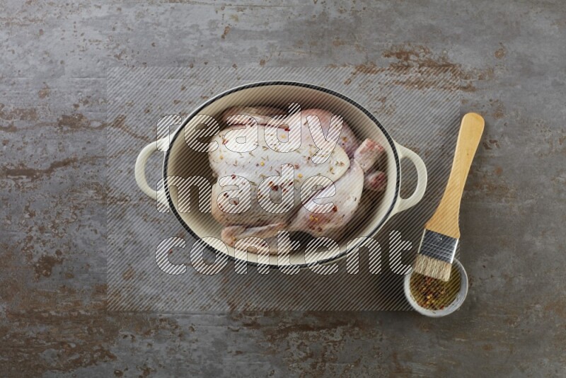 whole raw chicken on in a white ceramic pot direct on a rustic grey background