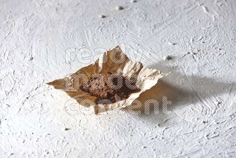 Cloves powder on crumpled piece of paper on a textured white flooring