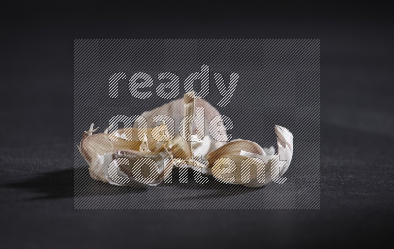 رأس ثوم مشقوقة تظهر الفصوص بداخلها على خلفية سوداء