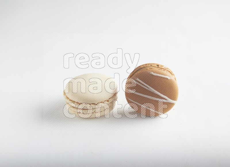 45º Shot of of two assorted Brown Irish Cream, and White Caramel fleur de sel macarons on white background