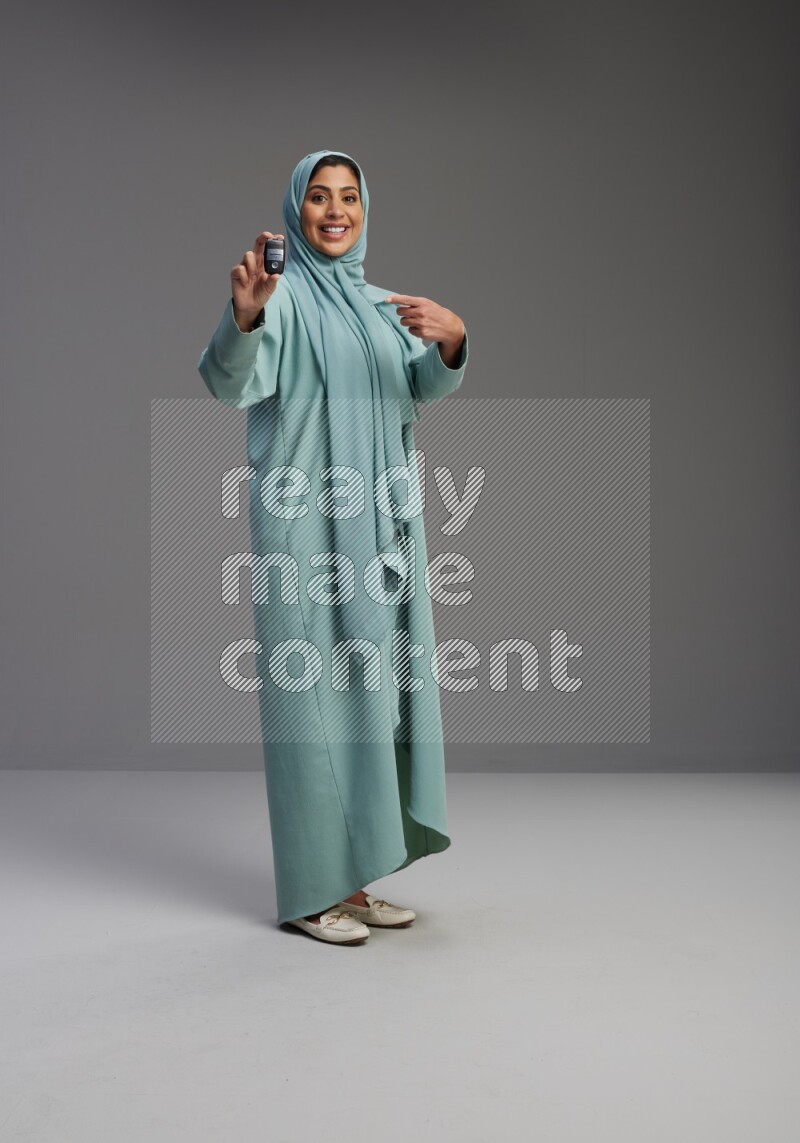 Saudi Woman wearing Abaya standing holding car key on Gray background