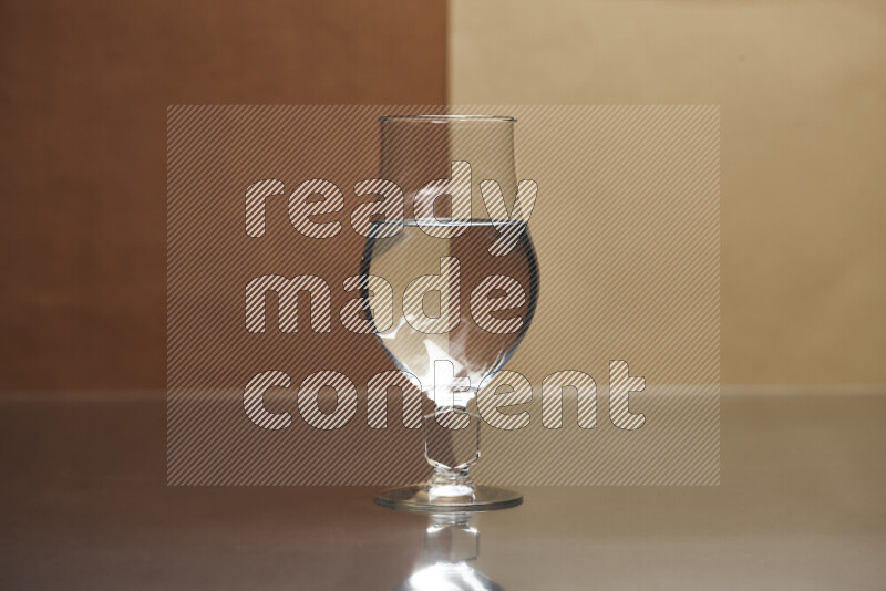 The image features a clear glassware filled with water, set against brown and light brown background