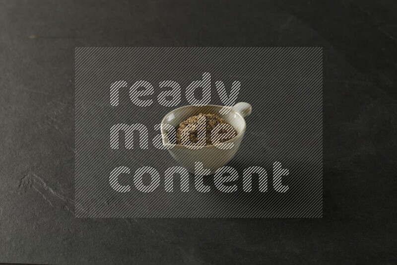 white ceramic round sauce bowl filled with herbs on grey textured countertop