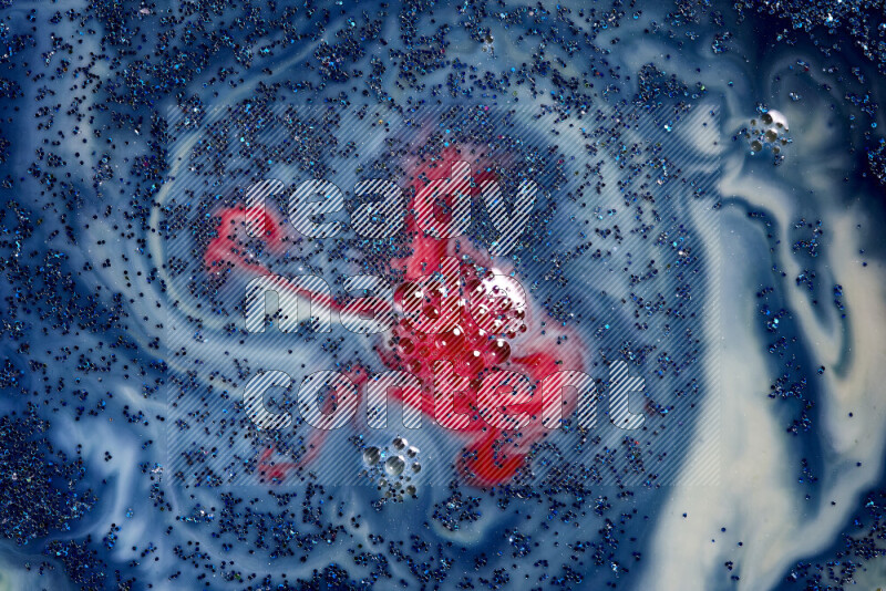 A close-up of sparkling blue glitter scattered on swirling blue and red background
