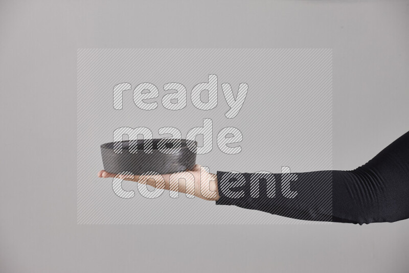 امرأة ترتدي عباءة سوداء تحمل أدوات فخارية مختلفة في أوضاع متعددة