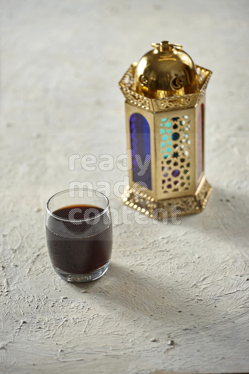 A golden lantern with different drinks, dates, nuts, prayer beads and quran on textured white background