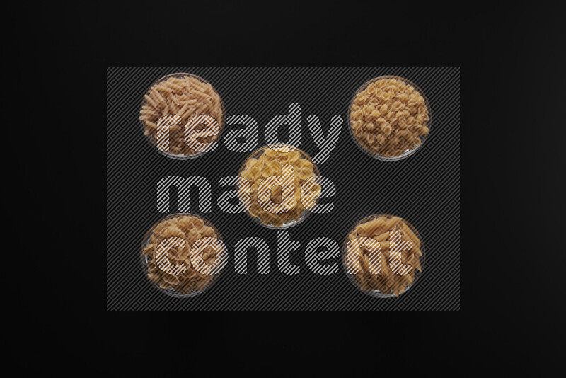 أنواع مختلفة من المعكرونة في أوعية زجاجية علي خلفية سوداء