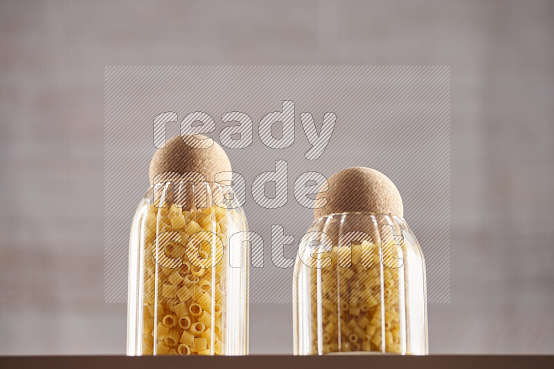 Raw pasta in glass jars on beige background