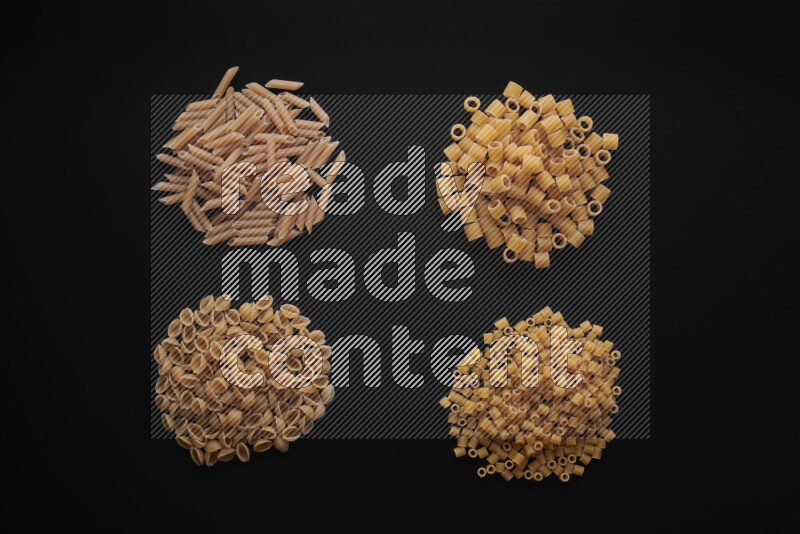 Different pasta types in bunches on black background