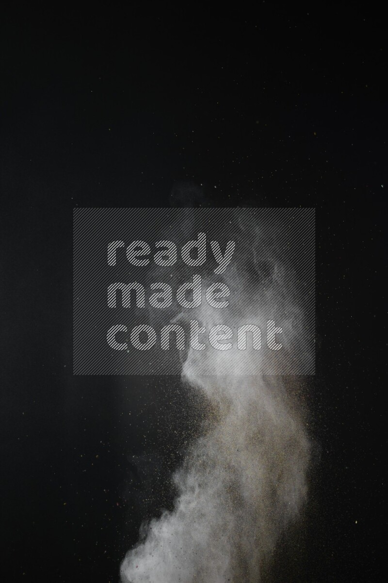 A side view of brown powder explosion on black background