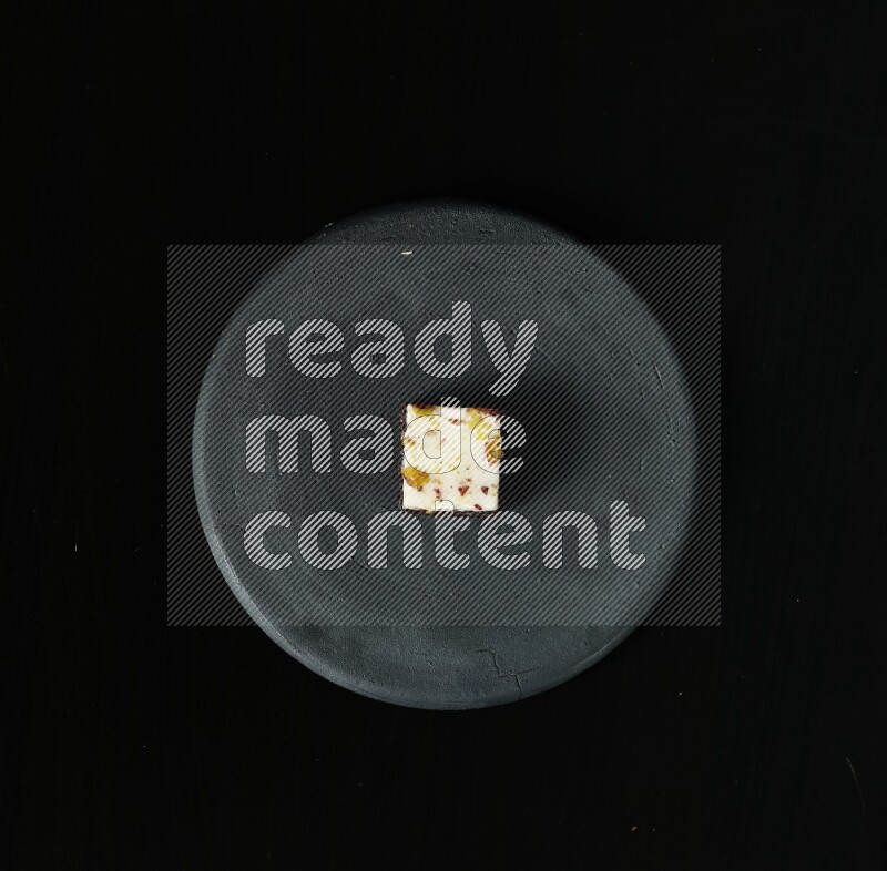 Assorted desserts in a black pottery plate on black background