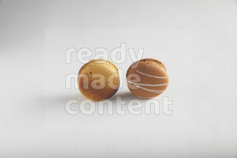 45º Shot of of two assorted Brown Irish Cream, and Yellow Crème Brulée macarons on white background