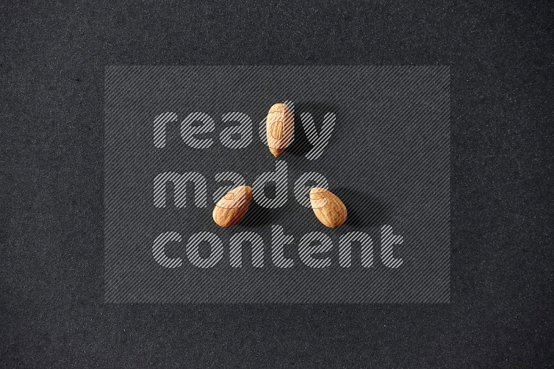 3 peeled almonds on a black background in different angles