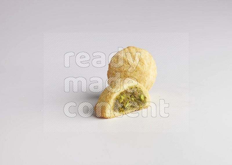 Two Pieces of Maamoul filled with pistachio paste  one of them is cut direct on white background