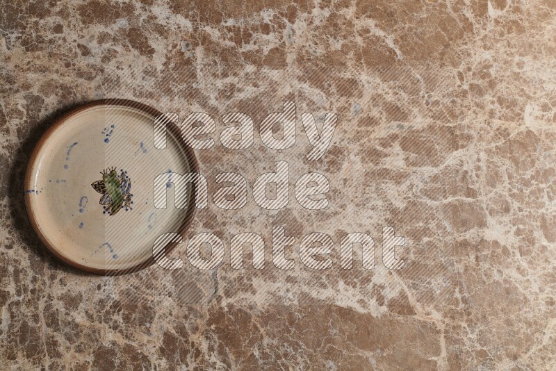 A decorative pottery plate on beige marble background