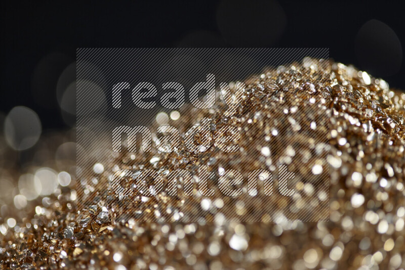 Gold shimmering fragments of glass scattered on a black background