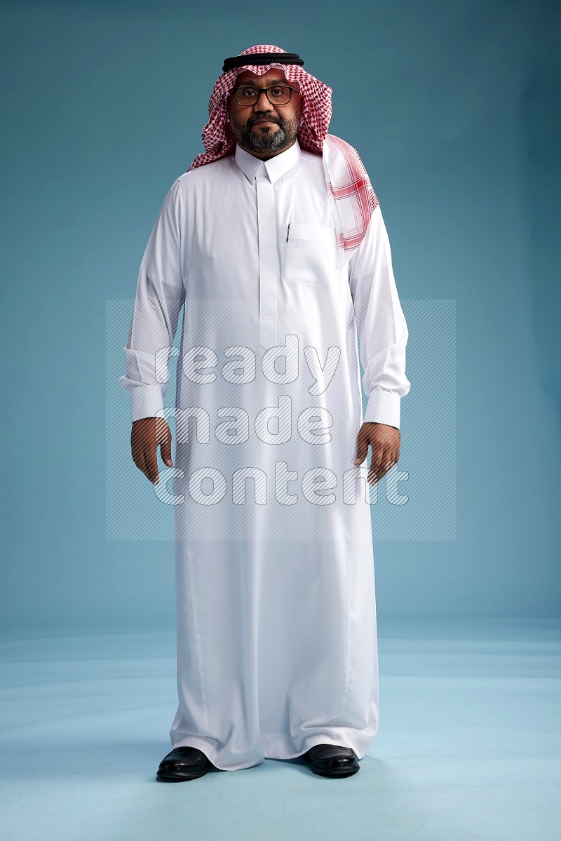 Saudi Man with shimag Standing Interacting with the camera on blue background