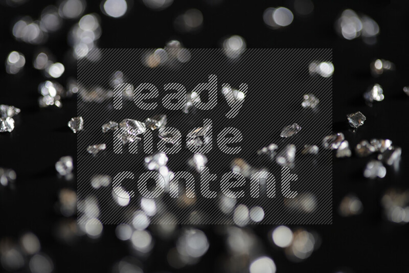 قطع زجاجية فضية لامعة متناثرة على خلفية سوداء