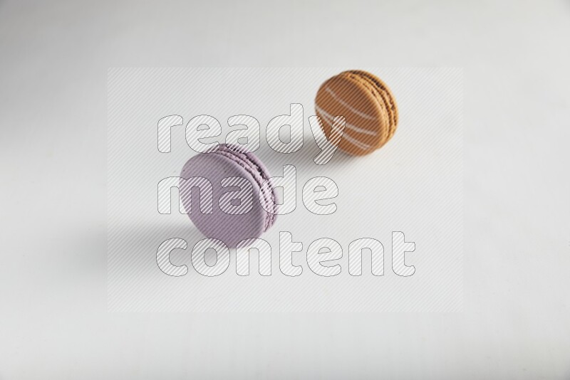 45º Shot of of two assorted Brown Irish Cream, and Purple Blueberry macarons on white background