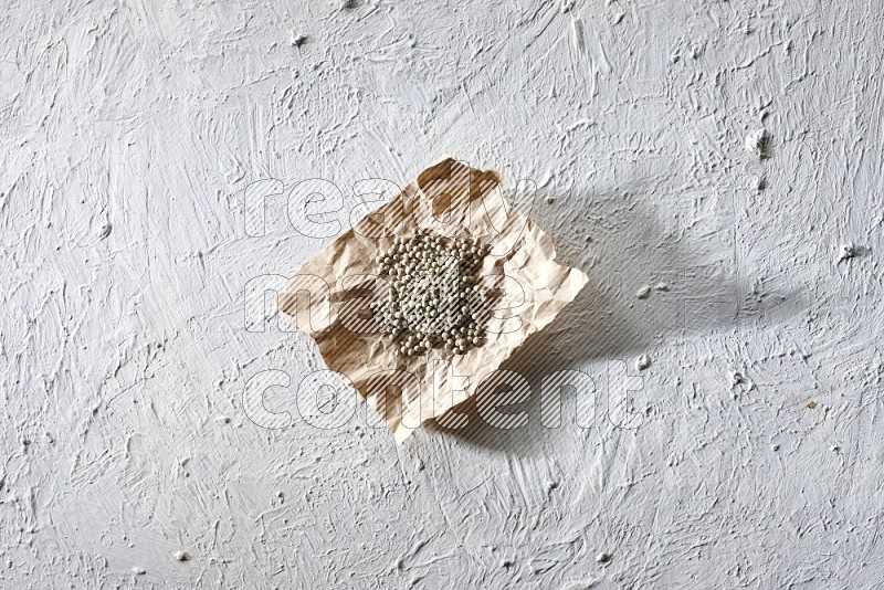 حبوب الفلفل الأبيض في قطعة من الورق على أرضية بيضاء