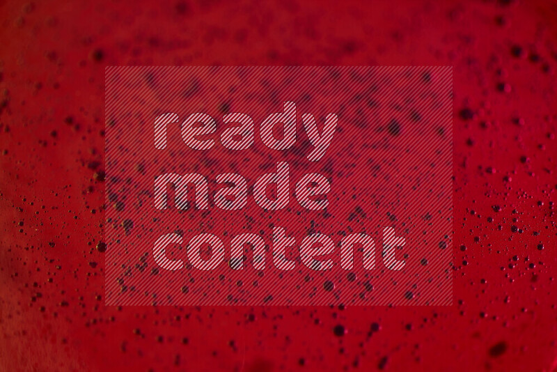 لقطات مقربة لقطرات ألوان مائية زرقاء على سطح الزيت على خلفية حمراء